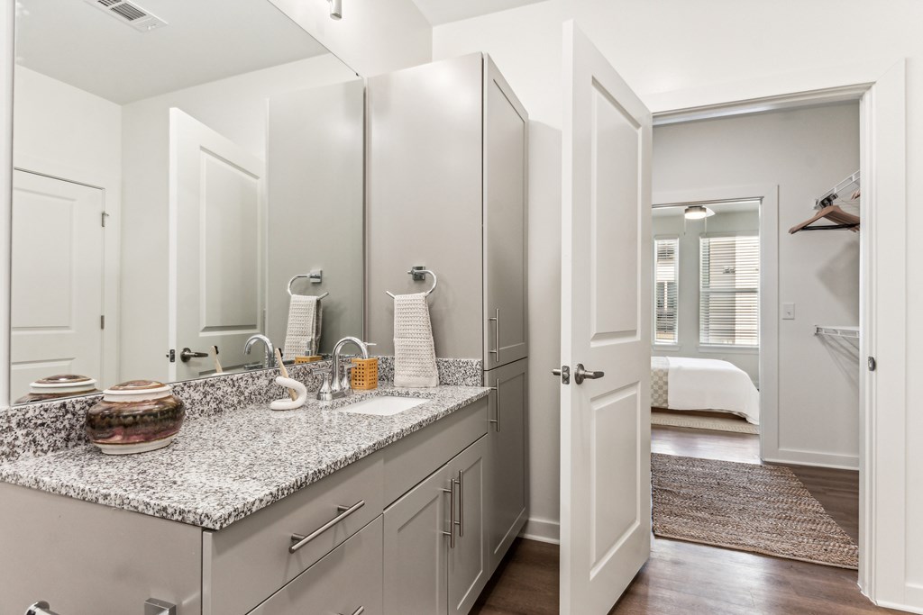 a kitchen with white cabinets and granite counter tops and a door to a bedroom
